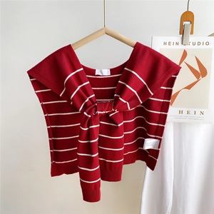 Detail of red and white striped knit shawl with a delicate bow tie on a wooden hanger