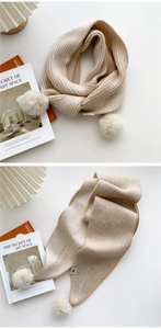 Détail de la maille rayée d'une écharpe d'hiver crème avec des pompons doux