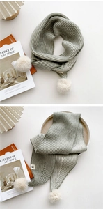 Détail d'une écharpe en maille côtelée vert-gris avec pompon en fausse fourrure