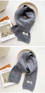 Close-up of chunky cable knit texture on dark grey winter scarf with YYDS patch