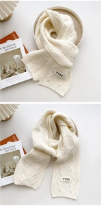 Close-up of cream knit scarf with textured twist pattern and YYDS woven label detail