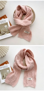 Detail of pink cable knit scarf featuring a white YYDS label and thick woven texture