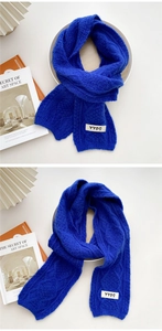 Detail of Klein blue knit scarf showing thick cable textures and white fabric label