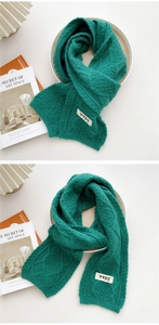 Close-up of deep green cable knit scarf featuring a white YYDS woven label detail