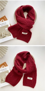 Detail of burgundy chunky knit scarf featuring cable texture and white label decoration