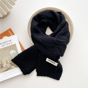 Chic black knitted scarf with YYDS woven label on a minimalist lifestyle setting