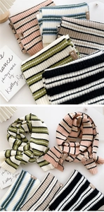 Detail of soft striped knit scarf showing thick ribbed texture and leather logo label
