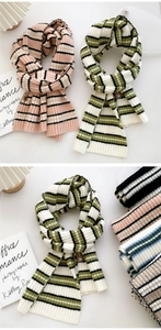 Detail of striped knit scarf texture with a small leather tag on a soft fabric edge