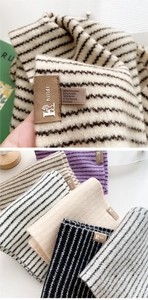 Detail of striped knitted scarves with leather brand label and material blend texture