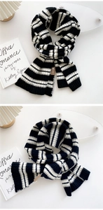 Detailed close-up of striped knit scarf featuring rib-knit ends and a brown leather tag