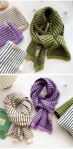 Detail of striped knit scarf with leather brand logo tag in warm green and lilac colors