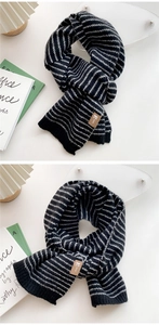 Detail of black and white striped knit scarf with a brown leather logo patch tag