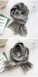 Close-up of gray and black striped knit scarf with decorative brown leather tag detail
