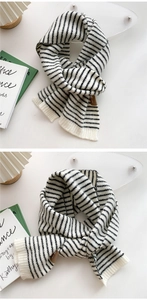 Detail of knit stripe scarf with brown leather label and soft thick texture