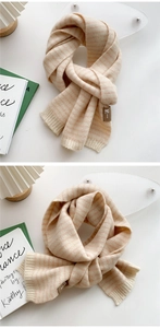 Detail of soft striped knit scarf in beige and pink with premium branded leather patch