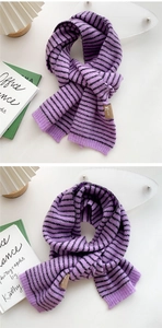 Detail showing soft purple striped knit texture and brown fabric label on winter scarf