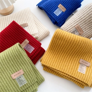 Close-up of thick knit ribbed scarves in multiple colors with leather logo labels