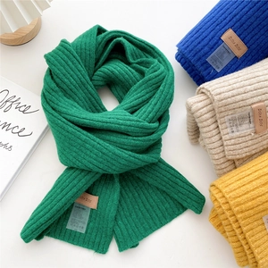 Thick knitted scarves in green, blue, oatmeal, and yellow with stylish leather labels