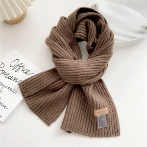 Detail of dark brown ribbed knit scarf showing texture with brand leather patch