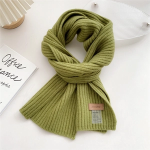 Macro detail of grass green ribbed knit scarf featuring a brown leather brand tag