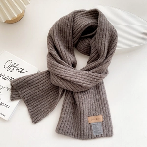 Detail of coffee-colored ribbed knit scarf with a leather brand tag and care label
