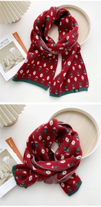 Detail eines dicken Strickschals mit rot-grünem Blumenmuster und geripptem Randdesign