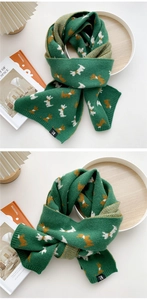 Nahaufnahme des dicken grünen Strickschals mit Hundemuster und H-Etikett-Detail