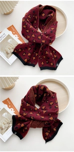 Details eines weinroten Strickschals mit Leopardenmuster und schwarzem Rippsaum