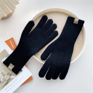 Close-up of black knitted gloves with premium brown leather label and warm ribbed cuffs