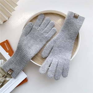 Detail of light grey knit glove texture with elastic ribbed wrist and brown leather logo