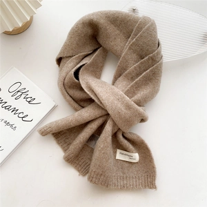 Detail of soft camel knitted scarf featuring a handmade fashion fabric label