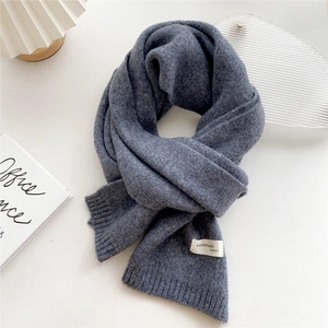Close-up of deep gray-blue knitted scarf detail with handmade fashion woven label