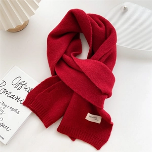 Detail of red knit scarf with handmade woven label and ribbed edge texture