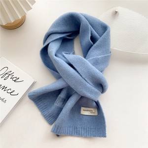 Detail of light blue knit scarf texture with handmade fashion label on white background