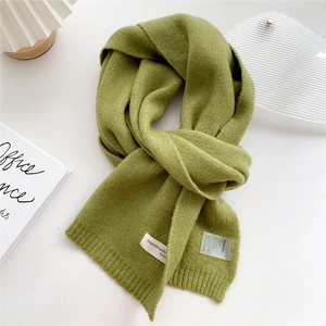 Close-up of grass green knitted scarf with handmade fashion tag and laundry label