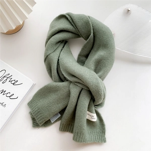 Close-up of sage green knitted scarf featuring a handmade fashion woven label and ribbed edges