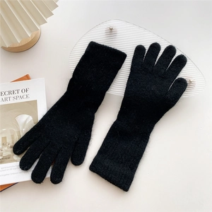 Detailed close-up of fuzzy black knit gloves with warm plush texture and ribbed wrist cuffs