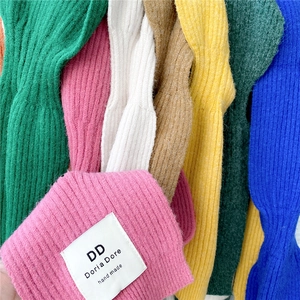Close-up of ribbed knit shawls in vibrant colors with handmade brand label detail