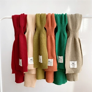 Vertical rib-knit solid shawls in multiple colors hanging on a minimalist display rack