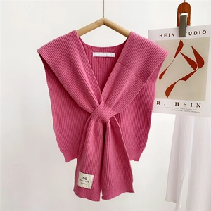 Detail of a pink ribbed knit shawl with V-neck cross design and a handmade label