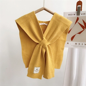 Close-up of yellow knitted cross shawl with vertical stripes and brand label