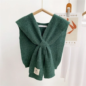 Detail of dark green knit shawl featuring a handmade label and thick crossover texture