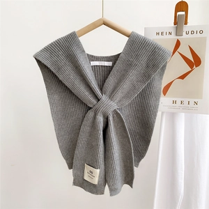 Detail of grey knitted shawl scarf with vertical stripes and front crossover knot design