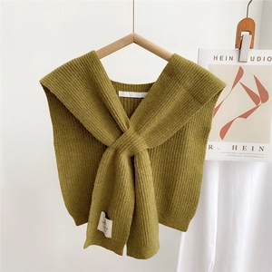Detailed knit texture of olive green crossover shawl featuring a minimalist woven brand label