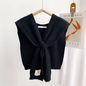 Detail of black ribbed knit shawl with handmade label and elegant draped texture