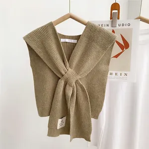 Close-up of khaki knitted cross-knot shawl with fine texture on a wooden hanger