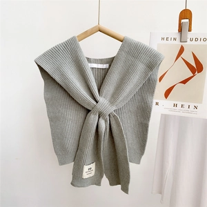 Close-up of grey knitted shawl wrap with vertical stripe texture and knot design details
