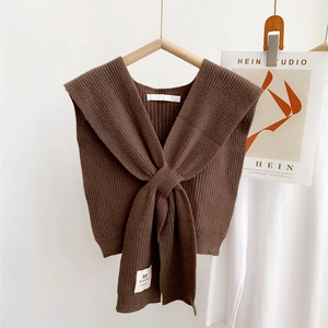Macro shot of dark brown knitted shawl with rib-knit texture and handmade logo tag