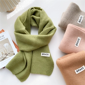 Thick knitted scarf with a vertical stripe pattern and a minimalistic white woven label
