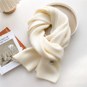 Close-up of off-white chunky knit scarf with ribbed texture and GRACE label detail